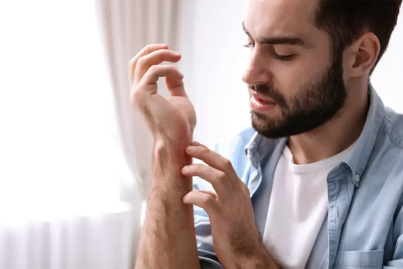 Young man scratching his hand.