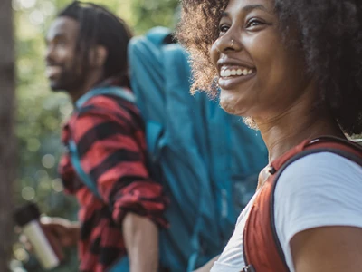A couple holding hands while walking through the woods.