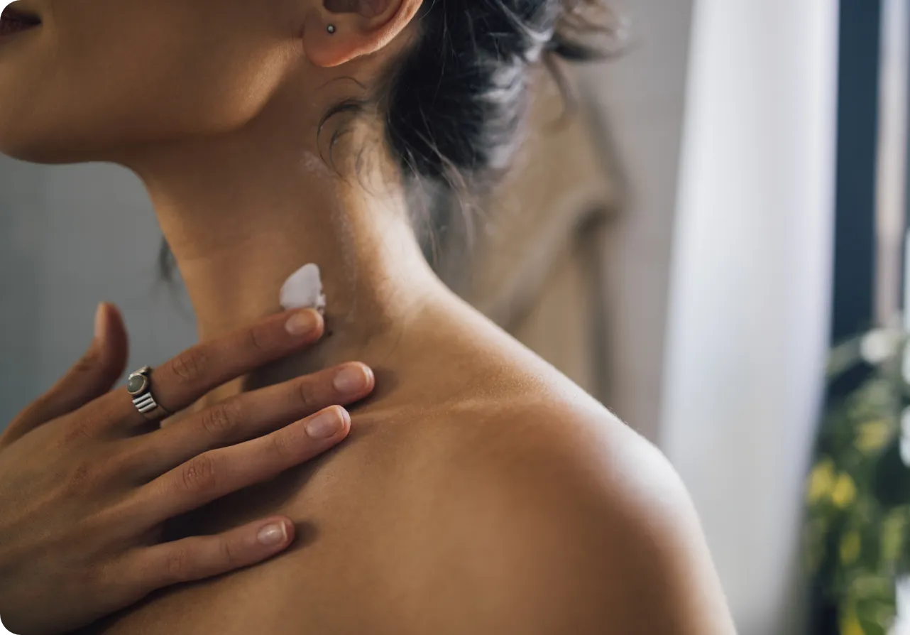 Close-up of a man's shoulder as she applies a bit of cream.