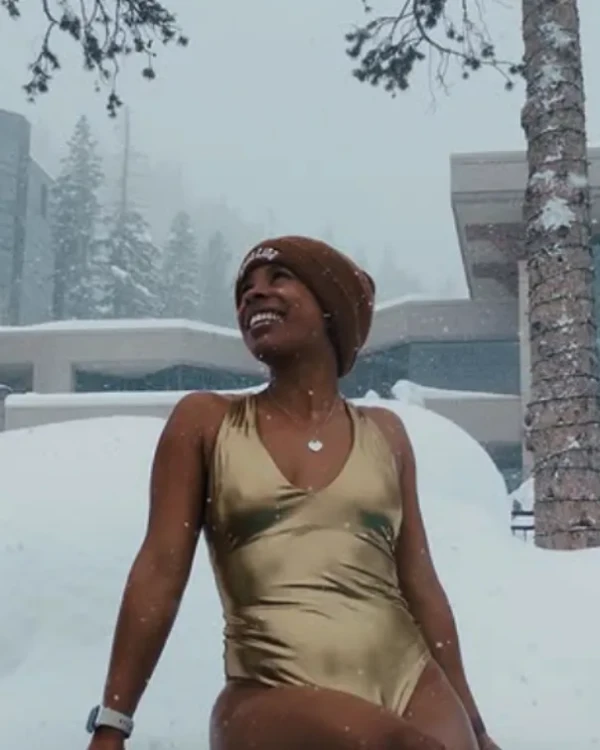 woman in a gold swimsuit, sitting in the snow.